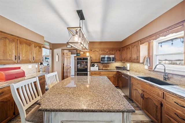 kitchen featuring a sink, stainless steel appliances, brown cabinets, and light stone counters