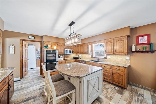 kitchen with a sink, tasteful backsplash, a center island, stainless steel appliances, and light wood finished floors