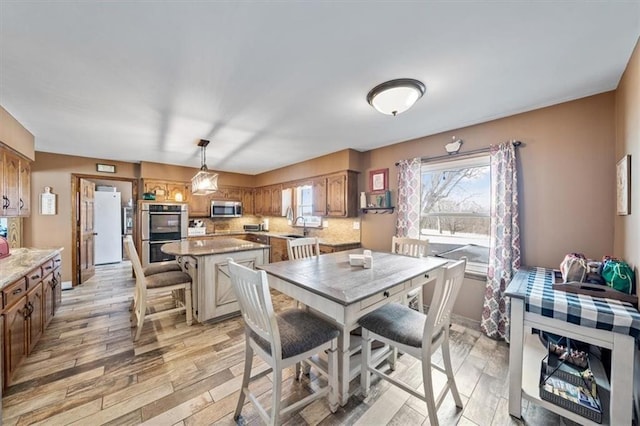 dining room with baseboards, plenty of natural light, and light wood-style flooring