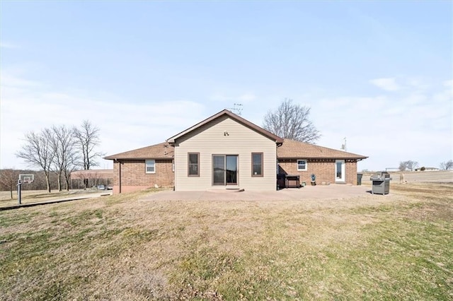 back of property with brick siding, a patio area, and a lawn