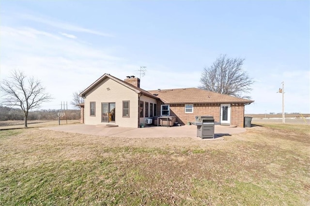 back of property with a patio area, a lawn, a chimney, and brick siding