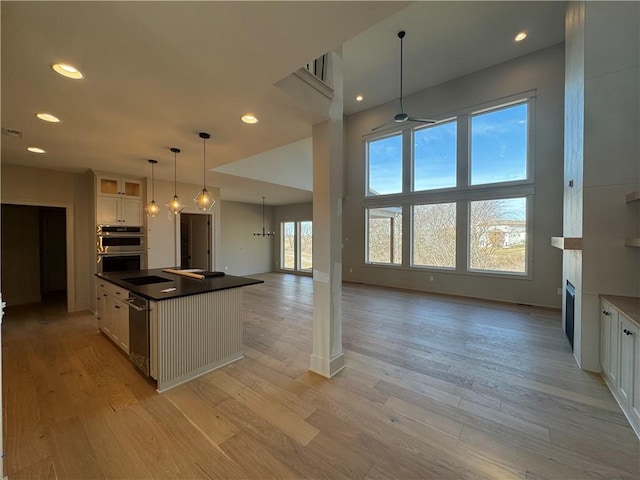 kitchen with stainless steel double oven, recessed lighting, white cabinets, dark countertops, and light wood-type flooring