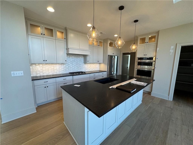 kitchen featuring dark countertops, wood finished floors, stainless steel appliances, and tasteful backsplash