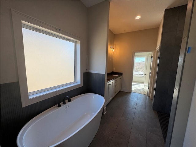 full bath with tile patterned floors, recessed lighting, a freestanding bath, and vanity