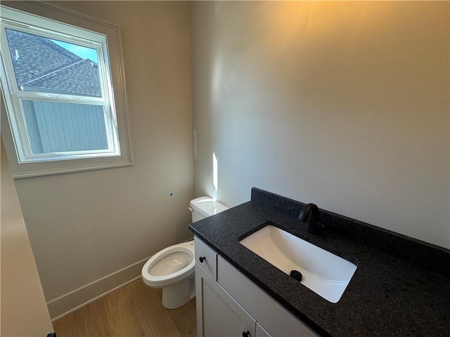 bathroom featuring vanity, toilet, wood finished floors, and baseboards