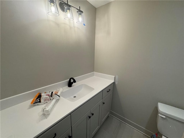 bathroom with baseboards, toilet, and vanity