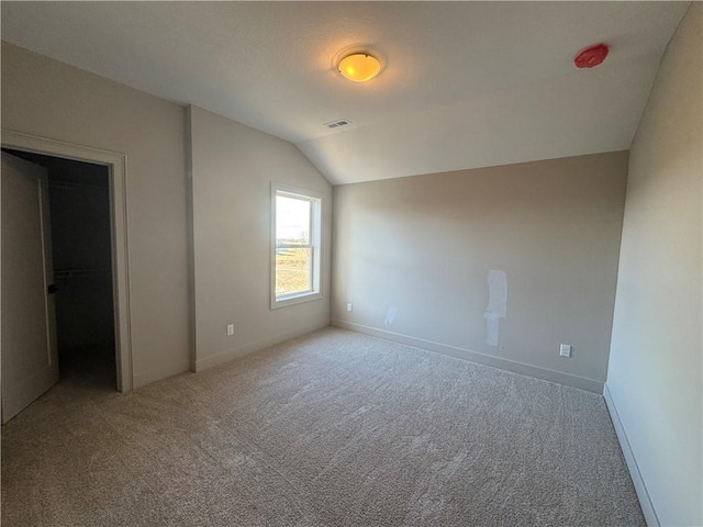 unfurnished bedroom featuring visible vents, baseboards, carpet, and lofted ceiling