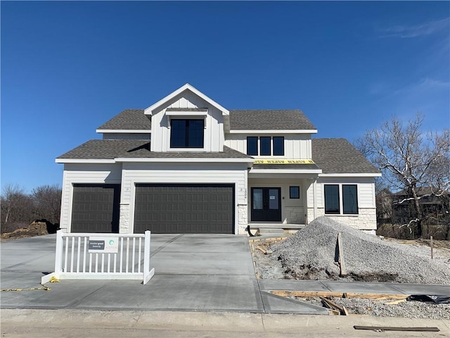 modern farmhouse style home with stone siding, board and batten siding, driveway, and roof with shingles