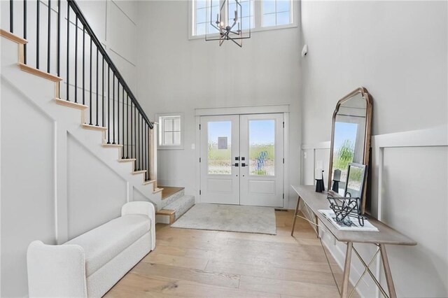 1506 NW 106th Ter, Kansas City, MO 64155 - entrance foyer featuring french doors, a towering ceiling, light wood-type flooring, an inviting chandelier, and stairs