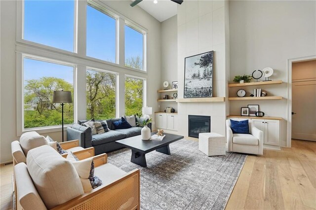 1506 NW 106th Ter, Kansas City, MO 64155 - living room with a high ceiling, built in shelves, a tile fireplace, a ceiling fan, and light wood-style flooring