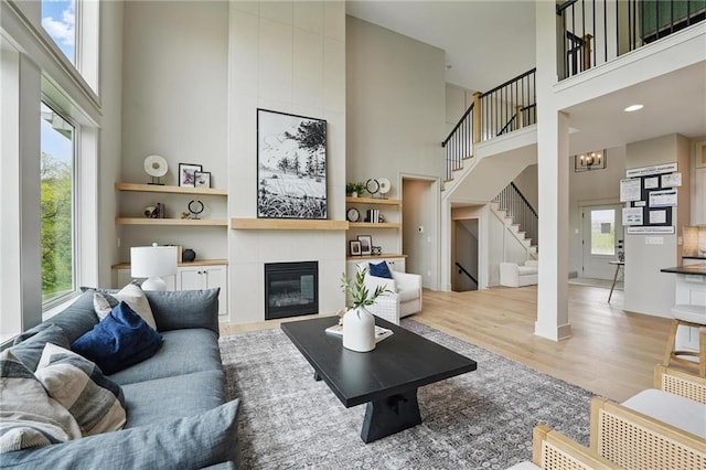 1506 NW 106th Ter, Kansas City, MO 64155 - living room featuring wood finished floors, stairs, a high ceiling, and a tiled fireplace