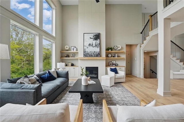 1506 NW 106th Ter, Kansas City, MO 64155 - living room featuring a tiled fireplace, wood finished floors, stairway, and a towering ceiling