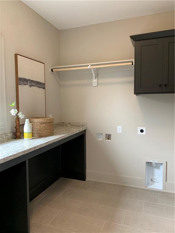 1506 NW 106th Ter, Kansas City, MO 64155 - laundry room with cabinet space, light tile patterned flooring, hookup for a washing machine, electric dryer hookup, and baseboards