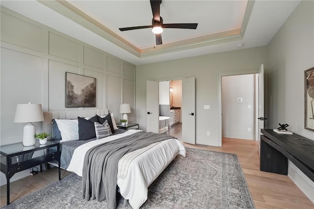 1506 NW 106th Ter, Kansas City, MO 64155 - bedroom featuring connected bathroom, a tray ceiling, ceiling fan, and light wood finished floors