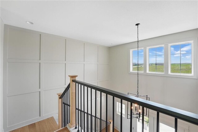 1506 NW 106th Ter, Kansas City, MO 64155 - hall featuring a decorative wall, light wood-type flooring, a chandelier, and an upstairs landing