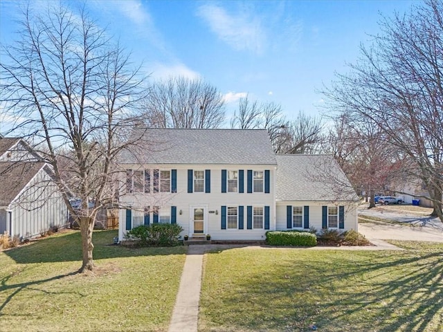 colonial inspired home with a front yard and a shingled roof