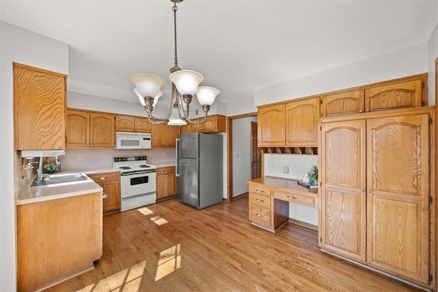 kitchen with tasteful backsplash, light countertops, light wood-style flooring, white appliances, and a sink