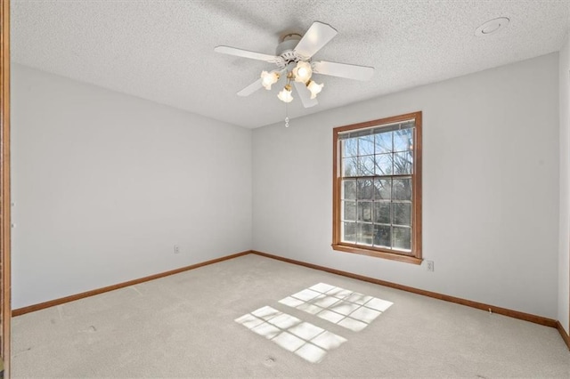 spare room featuring baseboards, light carpet, a textured ceiling, and a ceiling fan