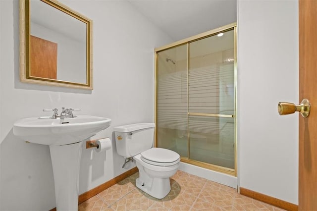 bathroom with a shower stall, toilet, baseboards, and a sink