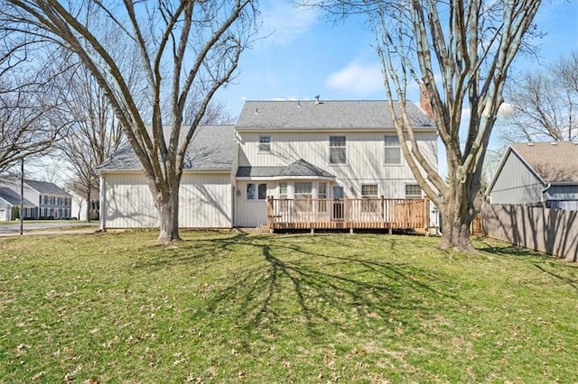 back of property featuring a wooden deck, a lawn, and fence