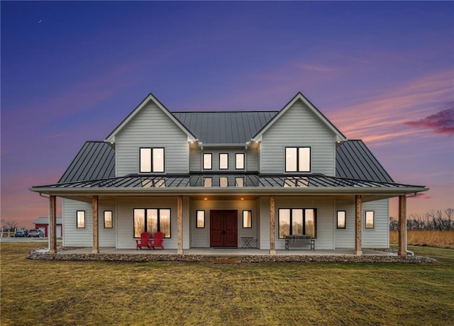 rear view of house with metal roof, a standing seam roof, and a lawn