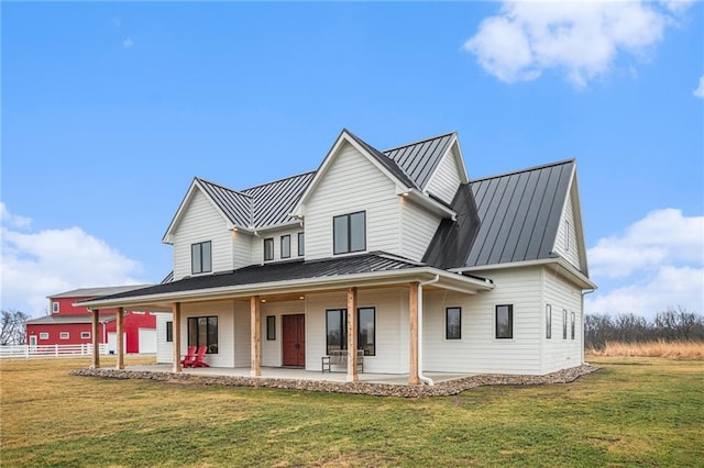 view of front of property featuring a front yard, a standing seam roof, metal roof, and fence