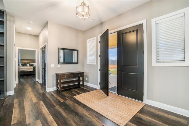 foyer featuring a notable chandelier, dark wood-type flooring, and baseboards