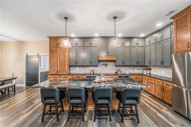 kitchen featuring tasteful backsplash, freestanding refrigerator, dark wood-style floors, and a barn door