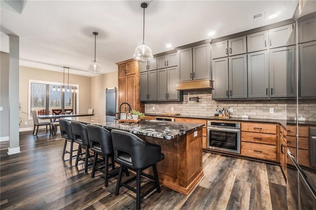 kitchen with premium range hood, dark wood finished floors, oven, and tasteful backsplash