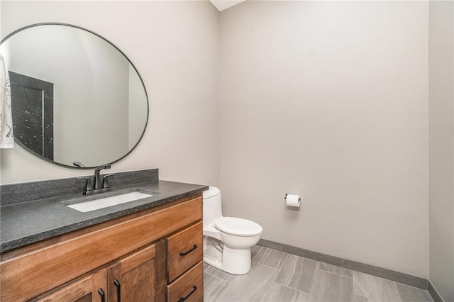 bathroom with toilet, baseboards, and vanity