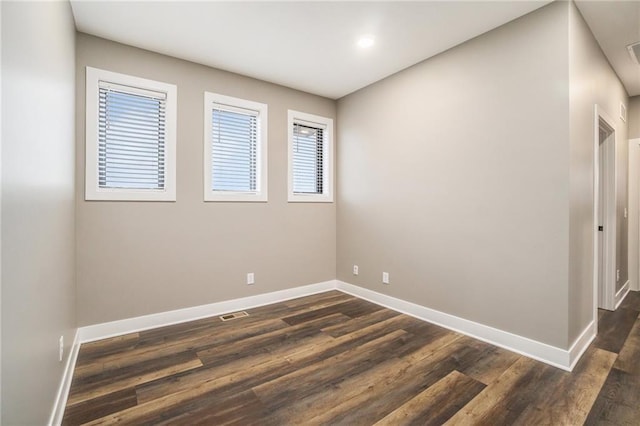 unfurnished room featuring dark wood-style floors, visible vents, and baseboards