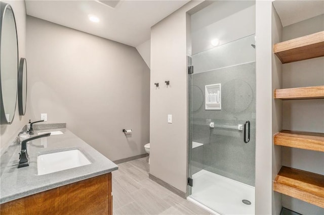 full bath featuring toilet, a stall shower, double vanity, and a sink