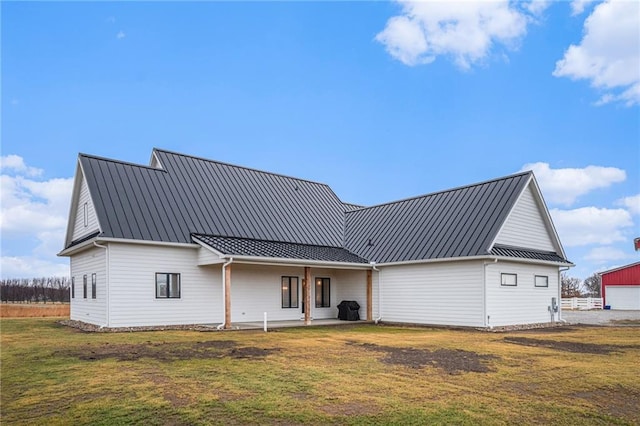 back of house with a standing seam roof, metal roof, and a yard