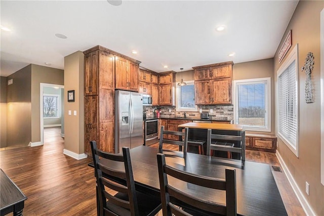 kitchen featuring visible vents, appliances with stainless steel finishes, backsplash, brown cabinets, and dark wood finished floors