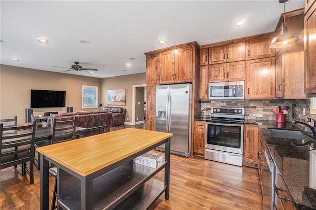 kitchen featuring tasteful backsplash, light wood-style flooring, brown cabinets, stainless steel appliances, and a sink