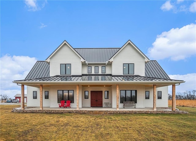 rear view of house featuring metal roof, a standing seam roof, and a lawn