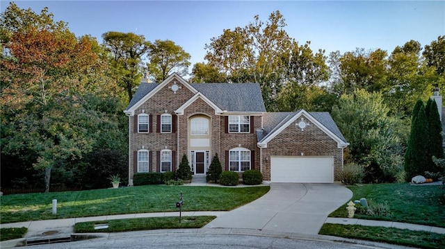 colonial inspired home featuring concrete driveway, a garage, brick siding, and a front lawn