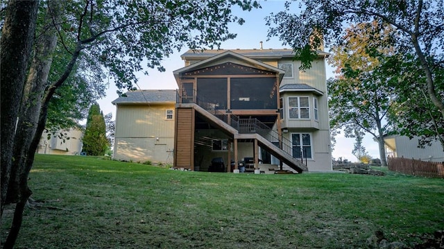 rear view of property with stairway, a lawn, and a sunroom