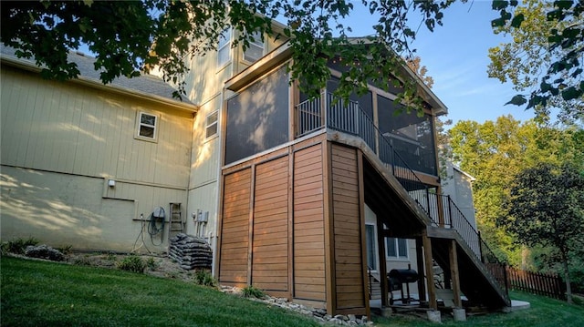 view of property exterior featuring stairs, a lawn, fence, and a sunroom