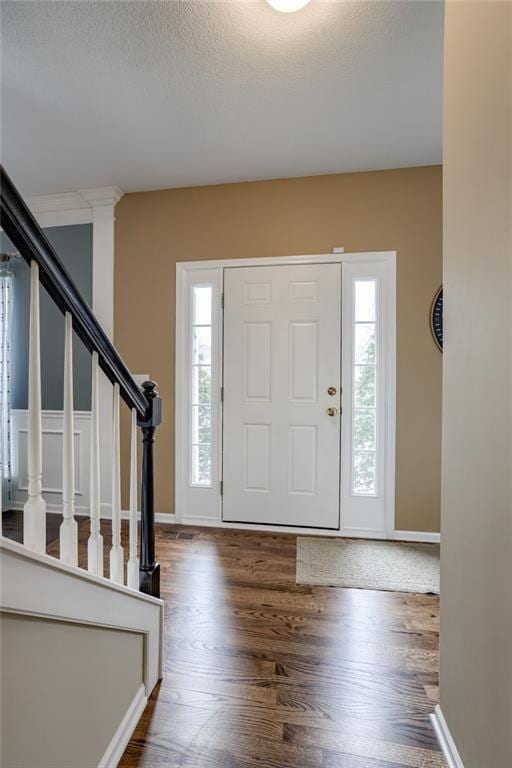 entrance foyer featuring stairway, a textured ceiling, and wood finished floors