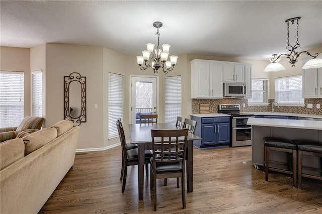 dining room with a notable chandelier, wood finished floors, and baseboards