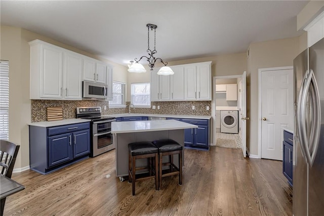 kitchen featuring blue cabinetry, appliances with stainless steel finishes, washer / clothes dryer, and white cabinetry