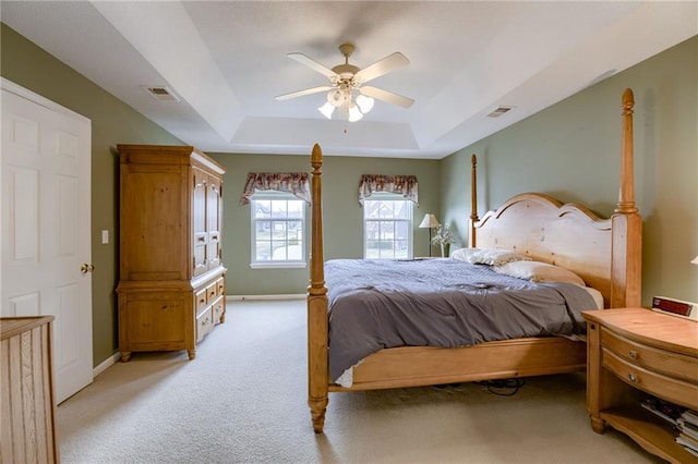 bedroom featuring a tray ceiling, visible vents, baseboards, and light colored carpet