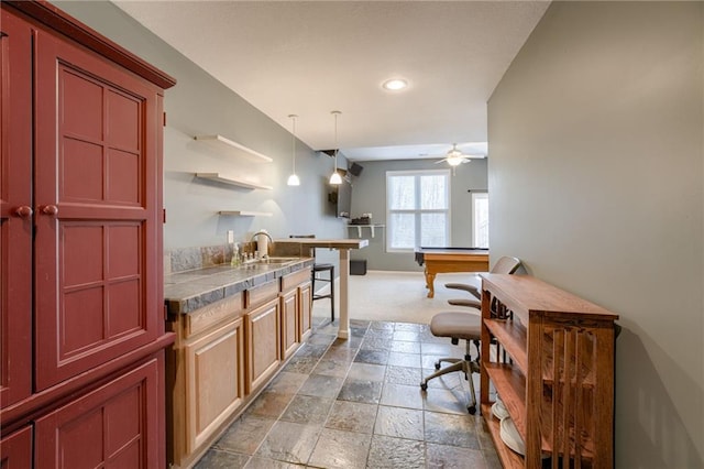 kitchen featuring a sink, open shelves, stone tile floors, ceiling fan, and hanging light fixtures