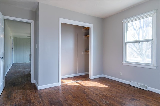 unfurnished bedroom featuring a closet, visible vents, baseboards, and wood-type flooring