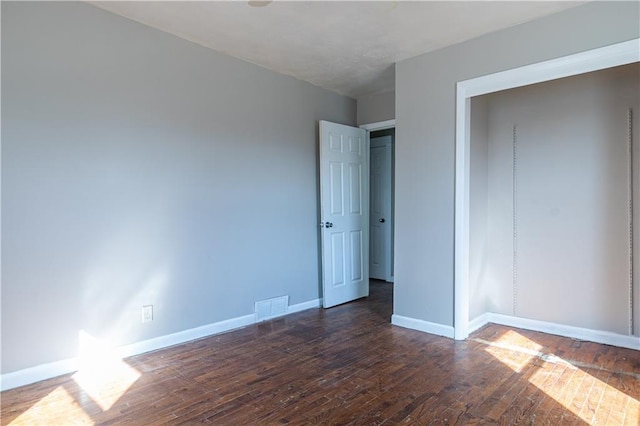 unfurnished bedroom featuring visible vents, baseboards, and dark wood-style flooring