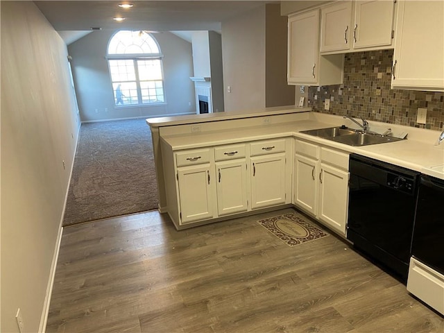 kitchen with black dishwasher, lofted ceiling, a peninsula, light countertops, and a sink