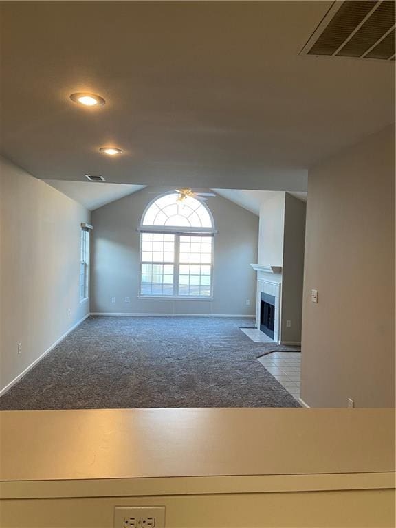 unfurnished living room featuring a fireplace with flush hearth, carpet, visible vents, and lofted ceiling