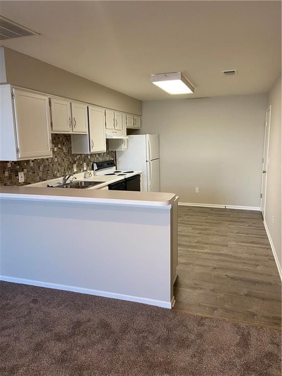 kitchen with a peninsula, white appliances, decorative backsplash, and light countertops