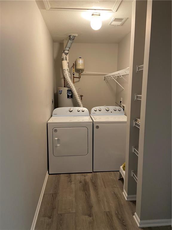 washroom featuring laundry area, wood finished floors, visible vents, baseboards, and washing machine and clothes dryer